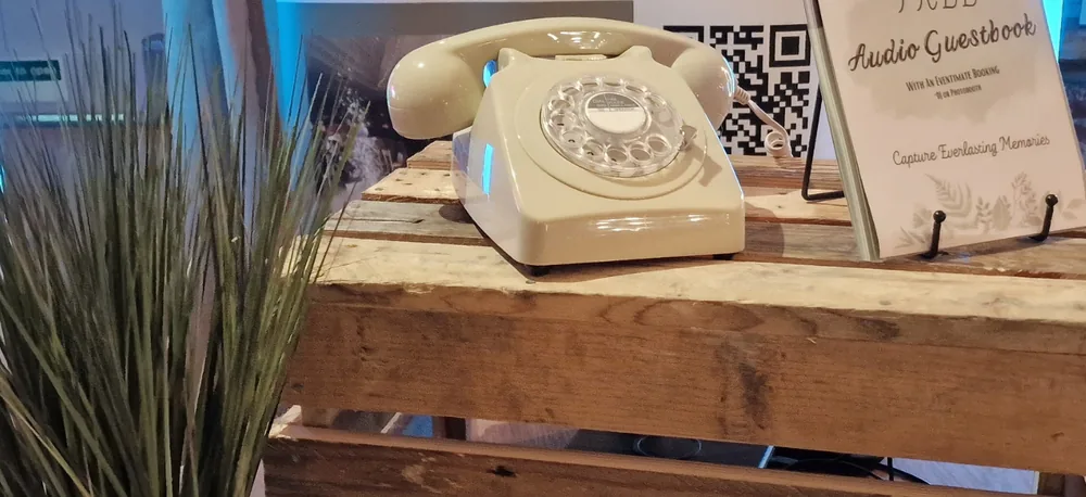 Cream rotary telephone audio guestbook displayed on wooden crates
