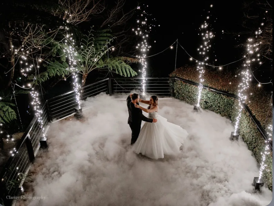 Wedding couple surrounded by cold spark fountains and low fog