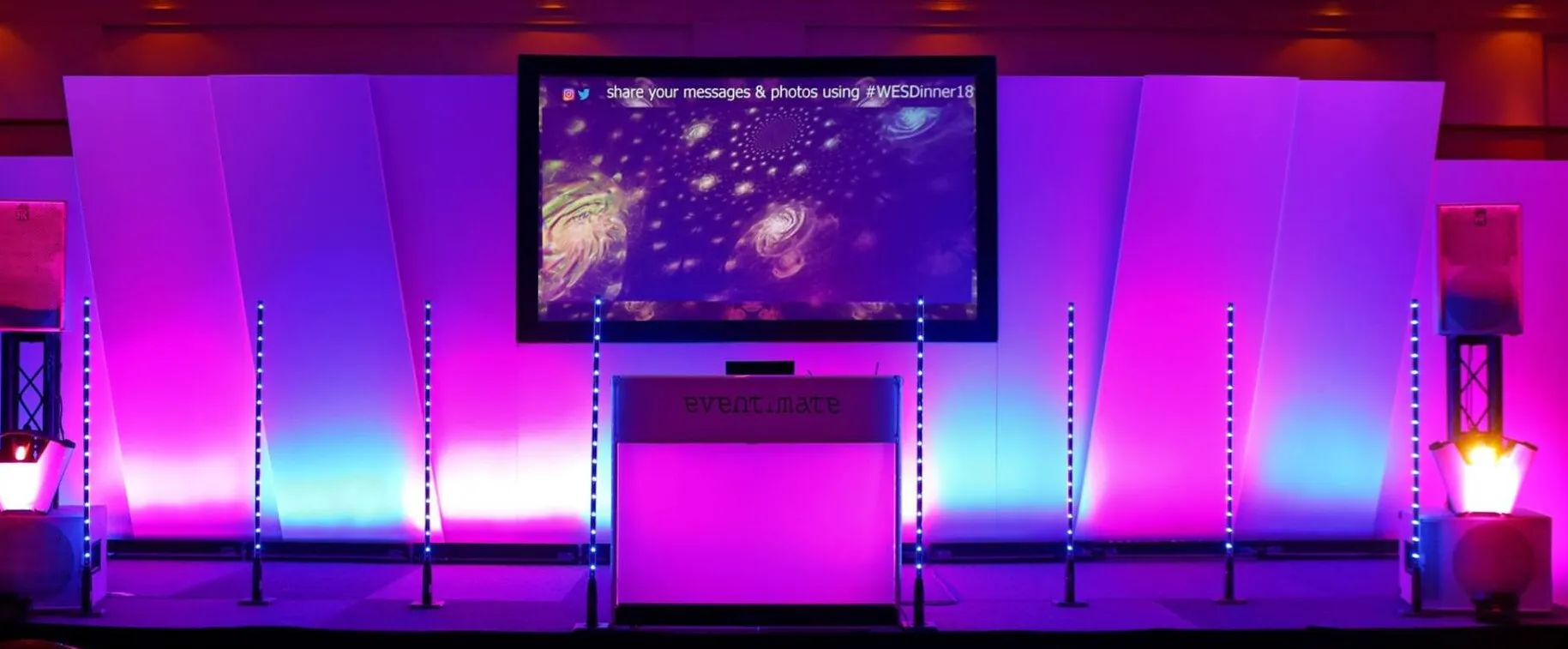 Eventimate DJ stage with a projection screen and purple and blue event lighting
